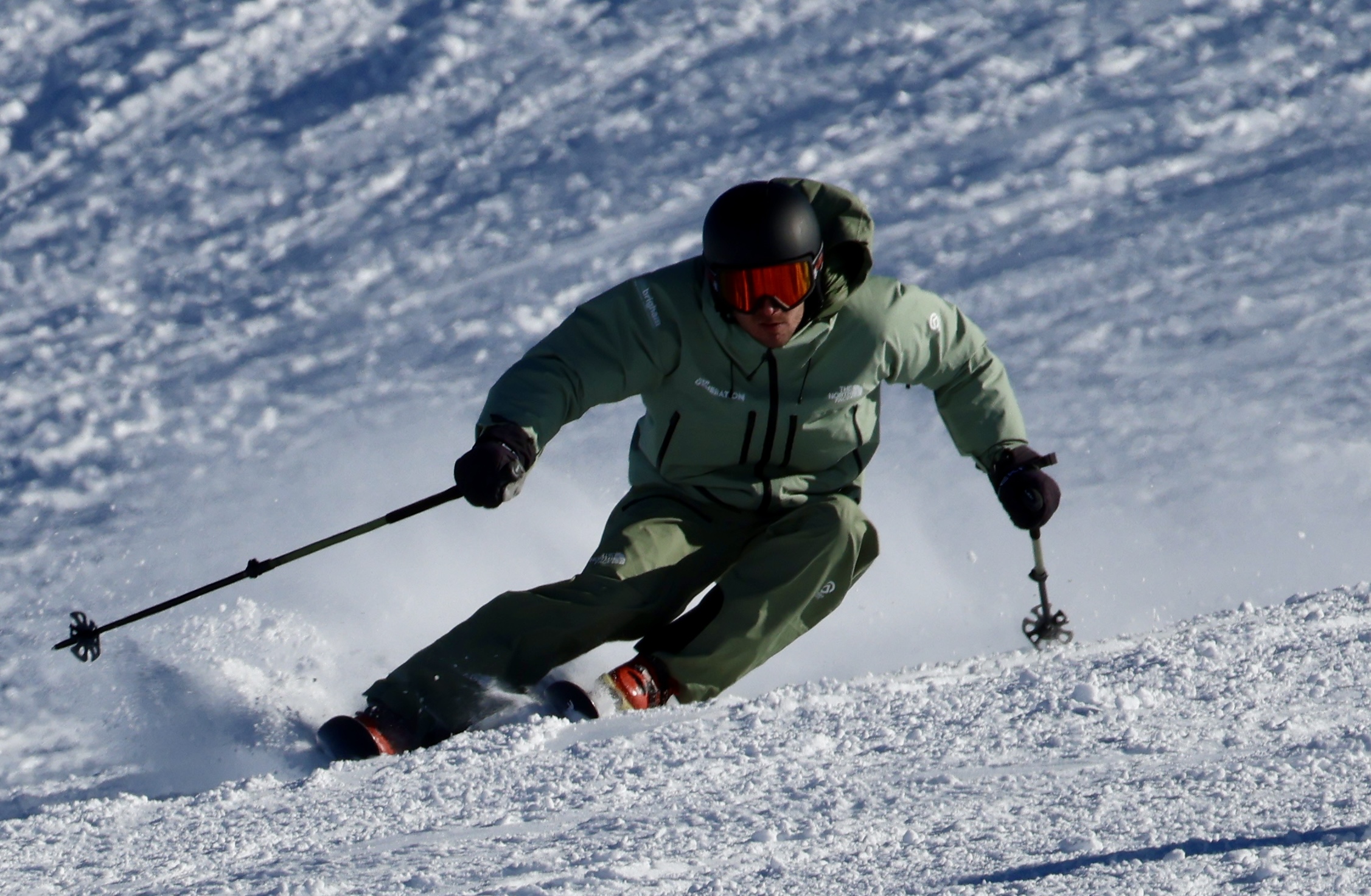 Skier carving in green jacket