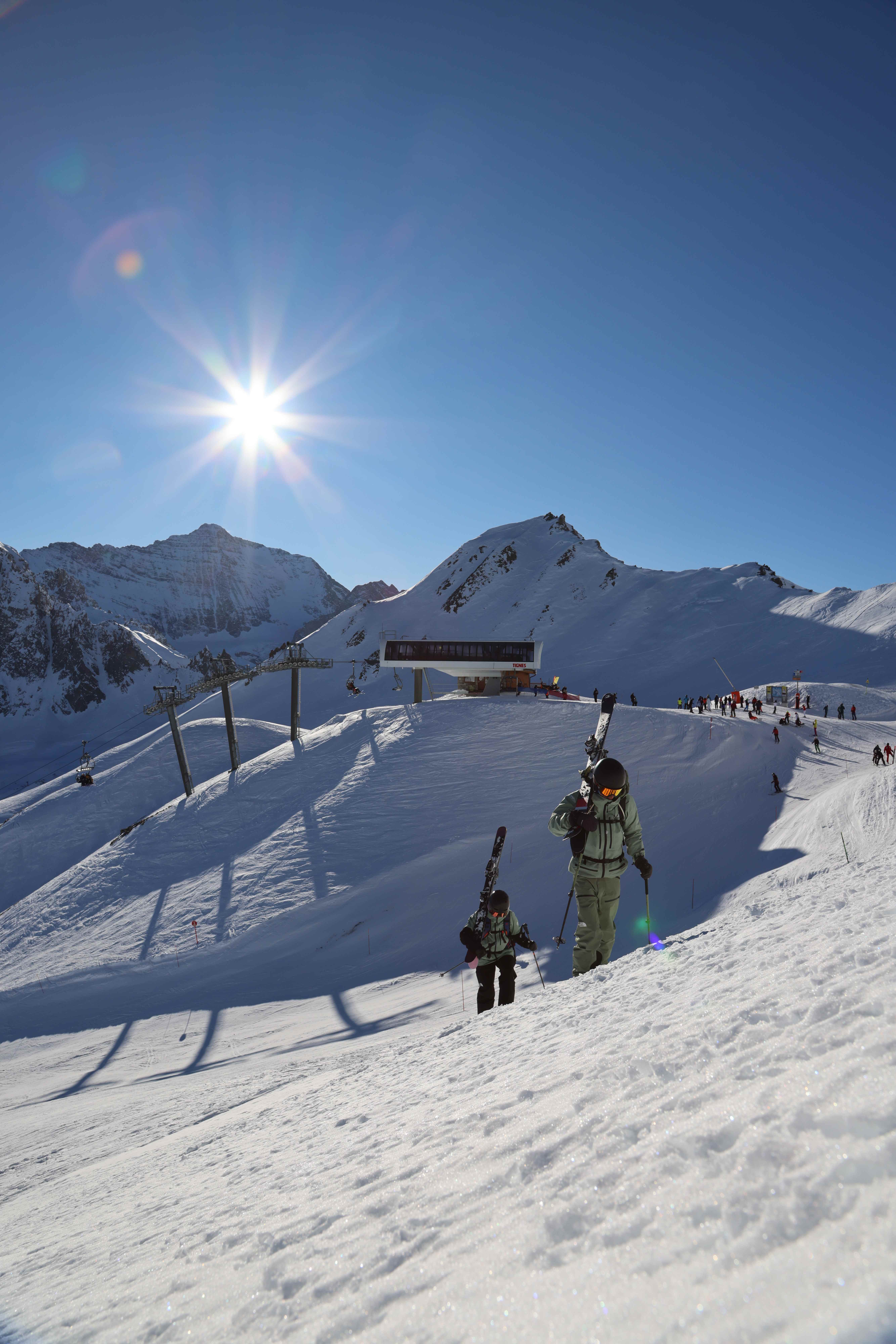 Skiers hiking up the slope at Tignes with sun flare