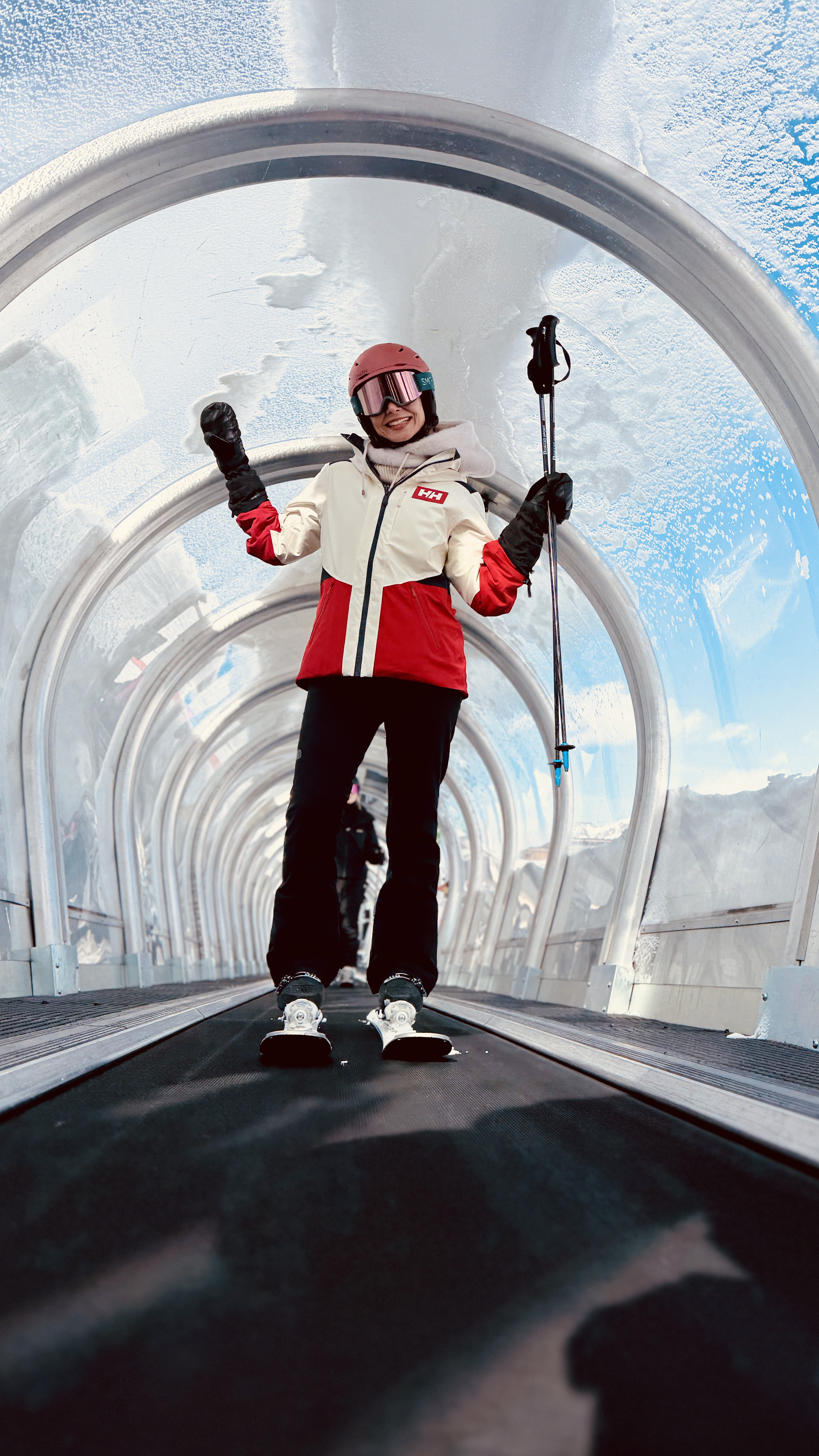 Joyful skier riding the covered magic carpet in Tignes